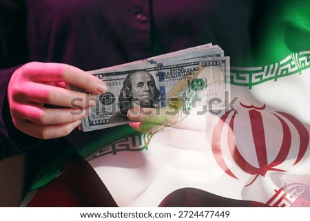 A person counts US dollars while standing in front of the Iranian flag. The scene shows the exchange of currency, illustrating financial relations.