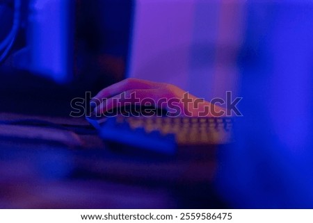 A person is currently engaged in using a computer mouse and keyboard while situated in a dimly lit room that lacks sufficient lighting