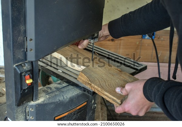 A
person cutting a board using a band saw- Arts and Crafts- DIY wood
working projects- cutting a piece of wood in a wood shop- making a
wooden craft using a bandsaw- cutting along a
line