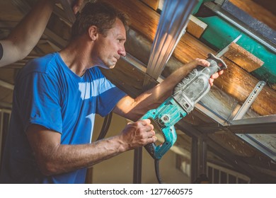 A person is cutting a board of wood next to a window with a reciprocating saw. Sawdust is flying around. Detail of a man cutting wooden board with strong back light to emphasize saw dust. - Shutterstock ID 1277660575