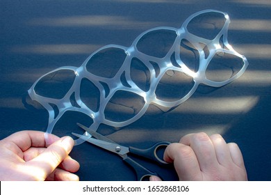 A Person Cutting A Eight Pack Rings Or Eight Pack Yokes With Scissors