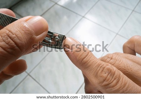 Person cutting long fingernails using metal steel nail clipper tool for personal hygiene care