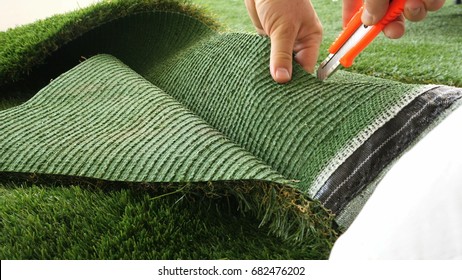 Person cutting sheet of artificial turf with knife