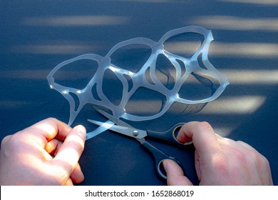 A Person Cutting A Six Pack Rings Or Six Pack Yokes With Scissors