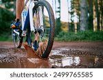 Person, cycling and mountain biking in nature with wheel, mud and splash for fitness, adventure and health. Cyclist, bicycle and exercise outdoor in forest for workout, sports and training with trees