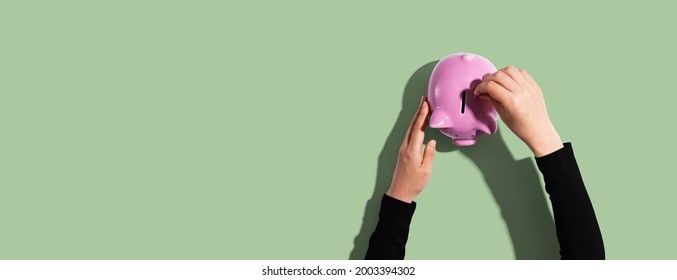 Person Depositing Money In A Pink Piggy Bank