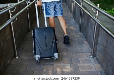 A person descends a ramp while pulling a carry-on suitcase, indicating travel or arrival.