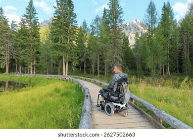 Persona con discapacidad en silla de ruedas navega por un camino de madera en los pintorescos Dolomitas. Rodeado de exuberante vegetación y montañas imponentes, el ambiente es sereno y tranquilo.