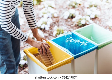 Person disposing of paper, throwing it into a yellow bin on terrace