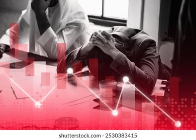 A person in distress at a desk, head in hands, with a declining stock chart overlay. Business stress, financial decline, and market downturn are depicted. - Powered by Shutterstock