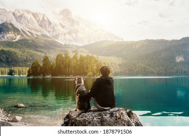 person with a dog in the mountains at a beautiful lake at sunset. Traveling with a pet. Happy satisfied time together. Friendship between man woman and dog. hugs. 