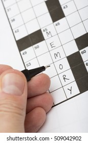 A Person Is Doing A Crossword Puzzle. It Is A Good Training For Brains Specially For Elderly People. The Word Memory Is Written On The Crossword Puzzle. Focus Point On The Pen Tip.