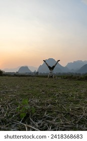 Person doing a handstand in a field at dusk with mountains in the background