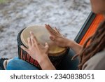 person with dreadlocks play tribal reggae at small African hand drum djembe