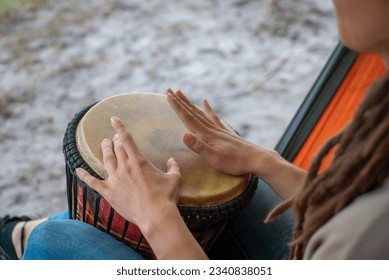person with dreadlocks play tribal reggae at small African hand drum djembe