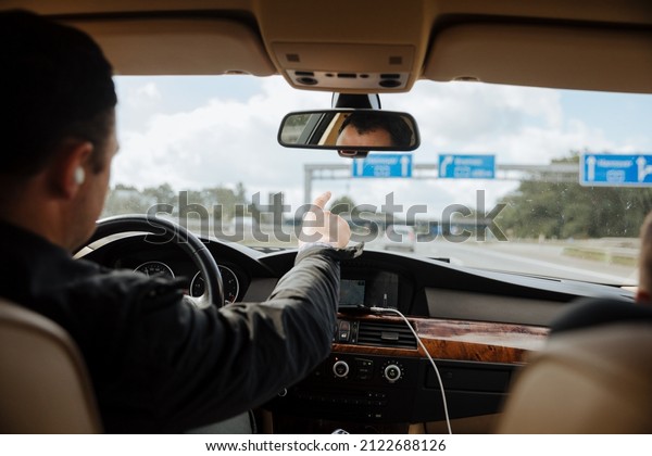 person driving a car. Driver shows\
something out the window. Driving on the Autobahn in Germany. Man\
points out of the car at the signs from the highway\
