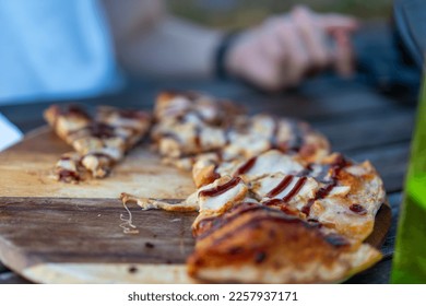 person eating a pizza with bbq sauce at an outdoor cafe - Shutterstock ID 2257937171