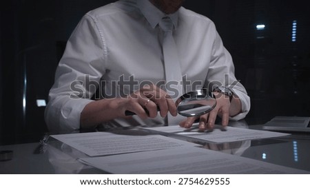 Person examining a document using a magnifying glass, focusing on fine print and terms in a legal agreement, working late. Audit and overworking concepts