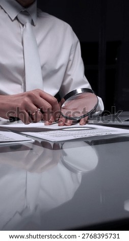 Person examining a document using a magnifying glass, focusing on fine print and terms in a legal agreement, working late. Audit and overworking concepts