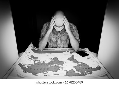 Person With Face Mask And Hand On His Head Looks Concerned To The World Paper Map. With Passport On It. Concept Of Cancelled Travel Plans Cause Of Sickness And Covid-19 Virus.