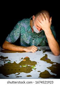 Person With Face Mouth Mask And Hand On His Head Looks Concerned To The World Paper Map. Concept Of Cancelled Travel Plans Cause Of Sickness.