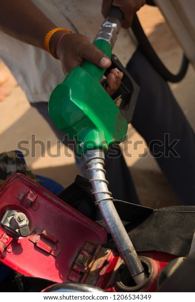 Person filling the Petrol using oil dispenser to bike\
petrol tank close up