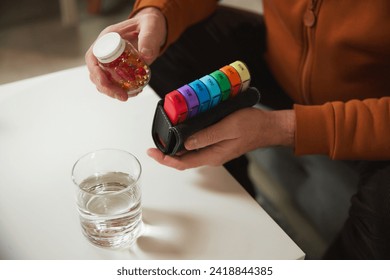 Person filling portable daily pill organizer from pill container, with other pill compartments. Concept of health and medical care, aging, medicine, treatment - Powered by Shutterstock