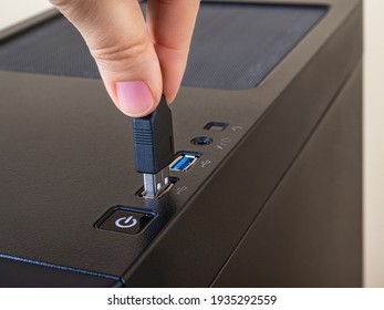Person fingers insert the USB cable into the top port on the computer tower case. Information transfer and storage device. Universal Serial Bus standard for PC cables and connectors. Front view. 