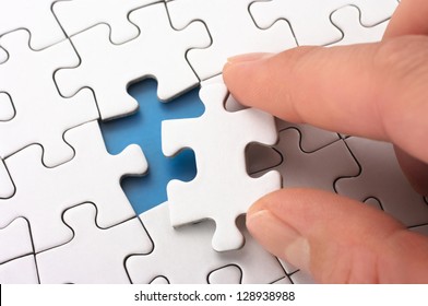 Person fitting the last puzzle piece.Concept image of building and button up.