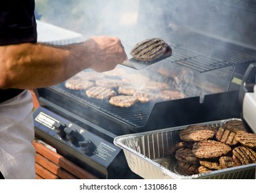 Person Flipping Burgers During BBQ Outdoors