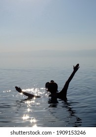 A Person Floating In The Dead Sea As The Sun Sets, Jordan.