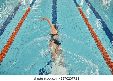 Person, freestyle and swimming in pool for sports competition, challenge and fitness training. Athlete, woman and swimmer in workout exercise for water race stroke, speed and triathlon championship - Powered by Shutterstock