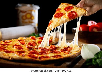 A person getting a piece of cheesy pepperoni pizza - Powered by Shutterstock