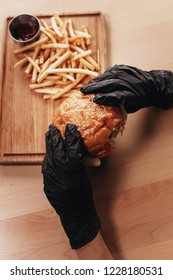 Person In Gloves Holding Tasty Burger Above Tray With French Fries