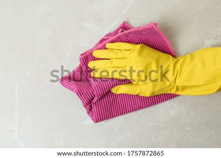 Person in gloves wiping grey marble table with rag, top view