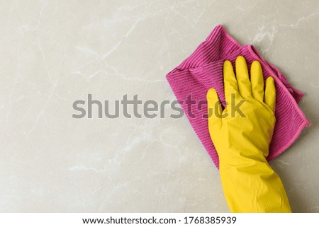 Person in gloves wiping grey marble table with rag, top view. Space for text