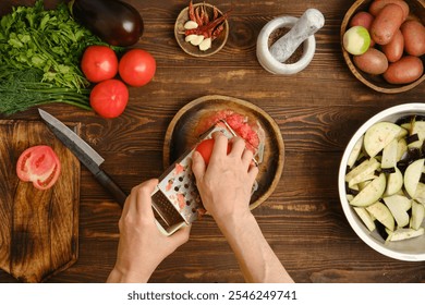 A person grates a tomato into a bowl while surrounded by fresh vegetables and herbs on a rustic wooden counter. The vibrant colors indicate a preparation of a delicious meal in a warm atmosphere. - Powered by Shutterstock