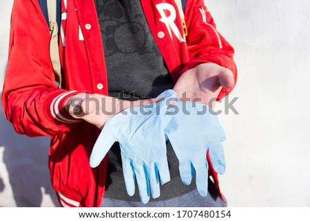 Person guy on the street is holding medical gloves. the guy is going to put on medical gloves during the coronavirus pandemic

