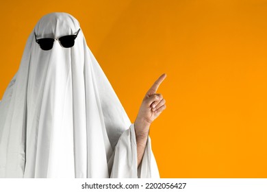 Person in Halloween costume of ghost with sunglasses points away - Shutterstock ID 2202056427