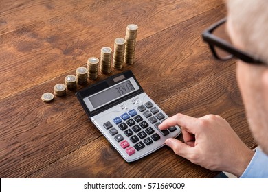 Person Hand Doing Calculation On Stacked Coin And Piggybank At Wooden Desk. Income Tax Concept - Shutterstock ID 571669009