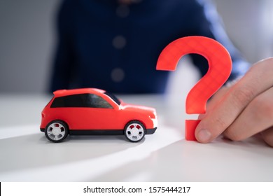 Person Hand Holding Question Mark Next To Car Model