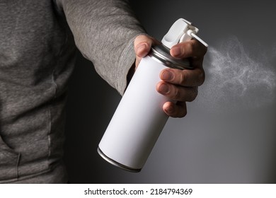Person Hand Holding And Spraying A Blank Aluminum Spray Can, Aerosol Can And Small Particles
