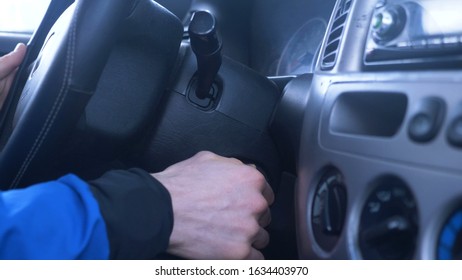 person hand inserts and turns ignition key in slot between leather steering wheel and modern dashboard closeup slow motion - Powered by Shutterstock