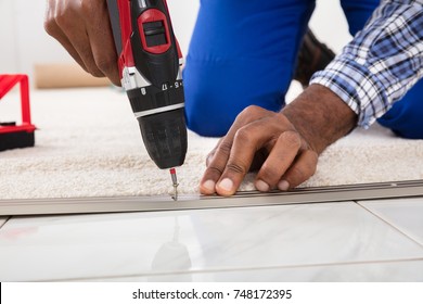 Person Hand Installing Carpet On Floor Using Wireless Screwdriver