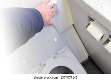 Person Hand Press Flush Button To Clean Toilet In Airplane Bathroom Interior Top Down View Of Passenger Aircraft Air Travel Equipment In Modern Water Closet WC With Open Seat Detail Inside Plane Cabin