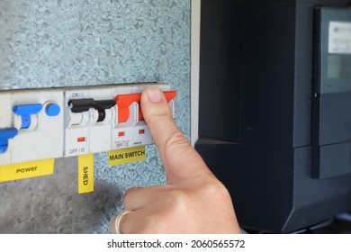 Person Hand Pressing And Switching  The Main Electric Power Button On A Home Electricity Fuses Switch Board. Power Cut And Energy Crisis And Great Reset Business Finance Concept. No People. Copy Space