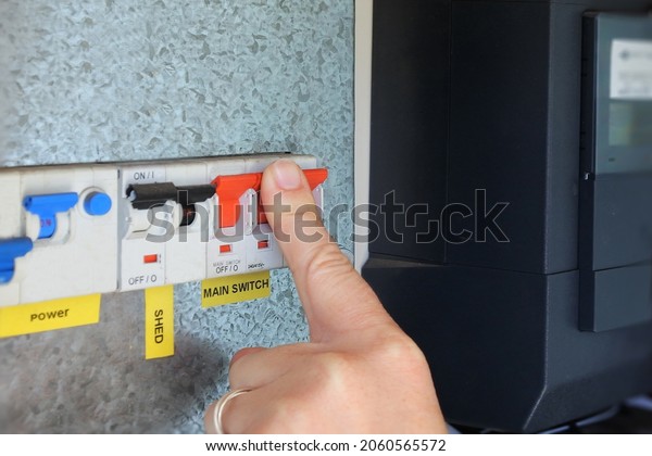 Person hand pressing and switching  the main\
electric power button on a home electricity fuses switch board.\
Power cut and energy crisis and great reset business finance\
concept. No people. Copy\
space