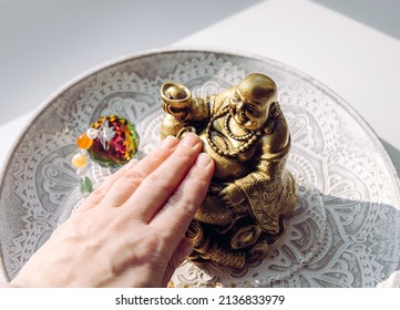 Person hand rubbing small golden laughing Buddha figurine tummy. It believed to bring happiness, good fortune and wealth. Buddai monk. - Powered by Shutterstock