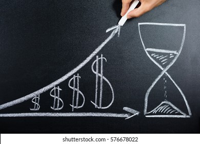 Person Hand Showing Dollar Growth Chart With Hourglass Drawn On Blackboard