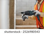 person hands hold hammer drill. Builder worker with pneumatic hammer drill perforator equipment making hole in wall at construction site